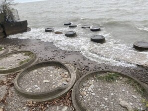 A beach with concrete rings and a rocky shoreline. - Lake Access Retreat Pet Friendly Fire Pit (Geneva)