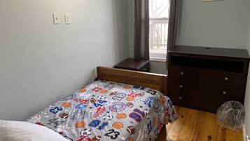 Cozy bedroom with a single bed, nightstand, and dresser, perfect for a restful stay.
