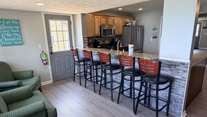 A kitchen with a central island, wooden cabinets, and a bar area with stools. - Lake Access Retreat  Pet Friendly  Fire Pit (Geneva)