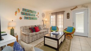A living room with a sofa, two armchairs, a coffee table, and decorative wall art.