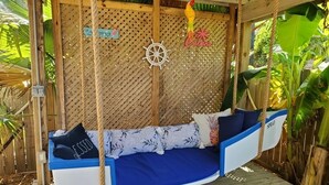 A blue and white swing bed with a 'Cayenne' sign, a ship's wheel, and a 'Spray' sign.