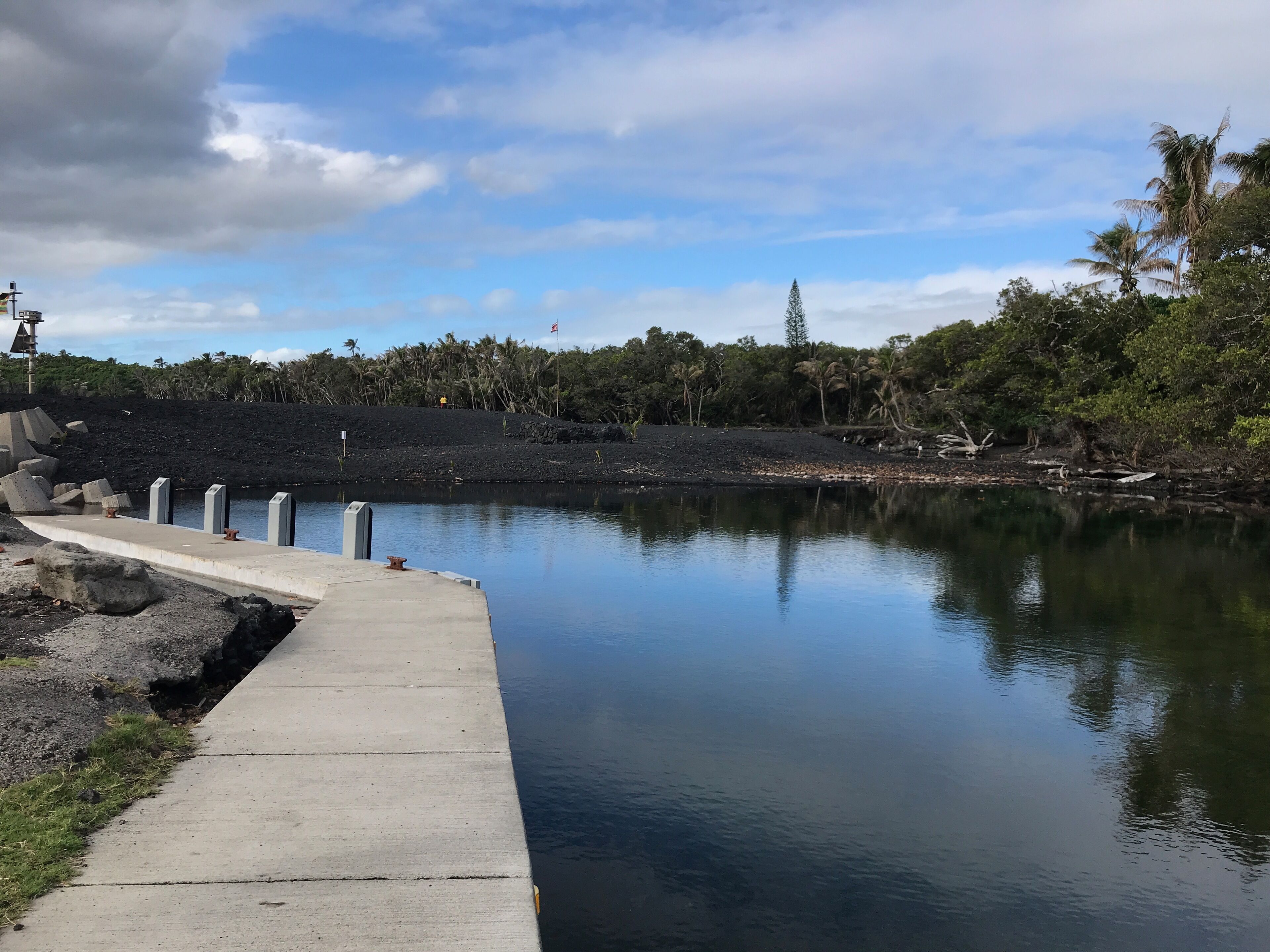 A calm lake with a concrete walkway and a rocky shoreline.