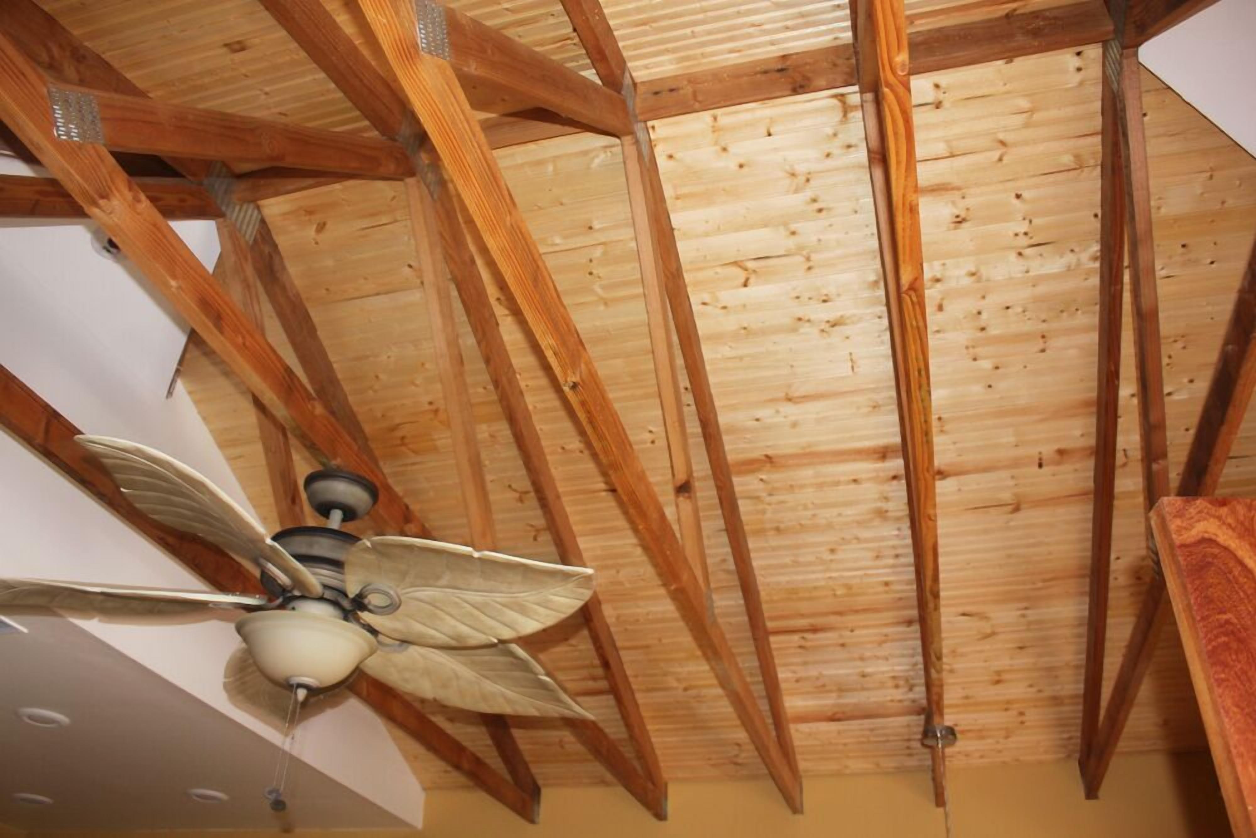 A ceiling with wooden beams and a ceiling fan.