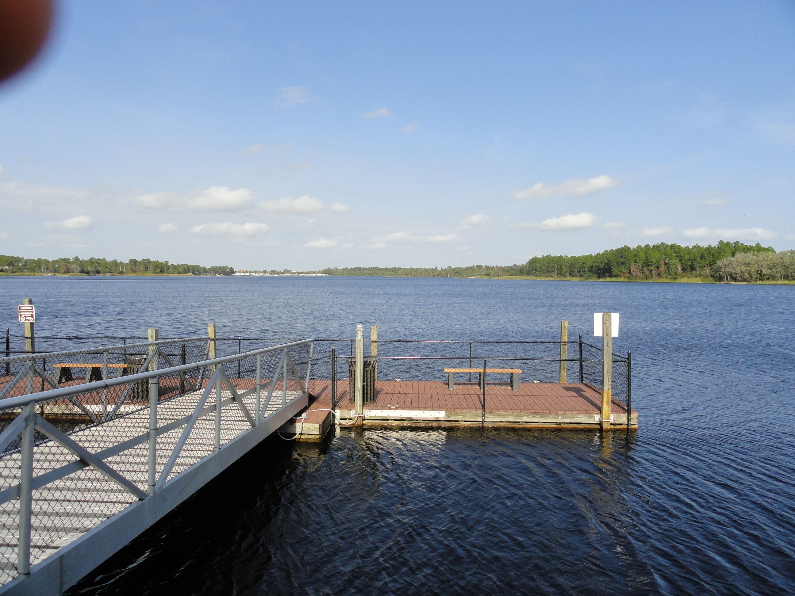 A wooden dock extending into a calm lake with a clear sky.