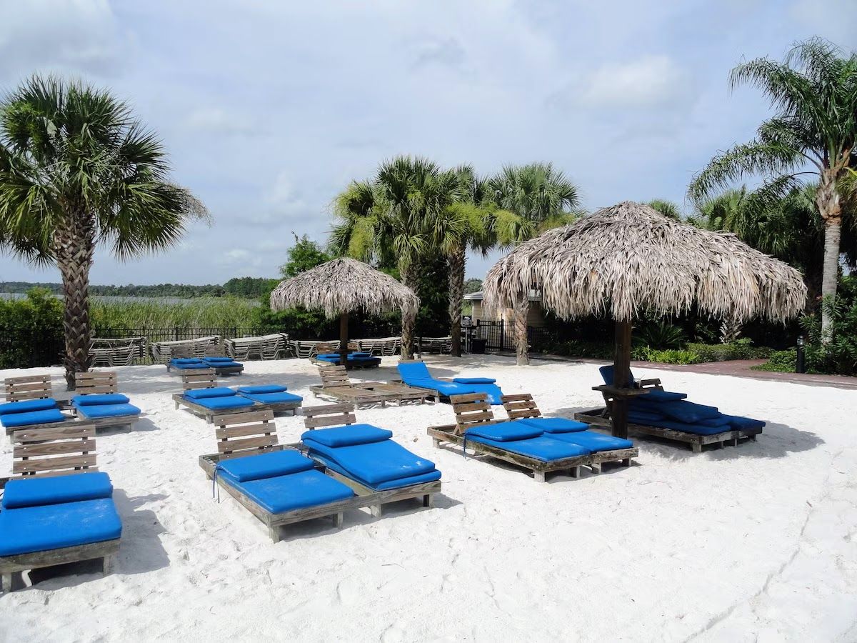 Ein Strandloungebereich mit Liegestühlen und Reetdachschirmen.