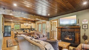 A cozy living room with a fireplace, wooden floors, and a dining area.