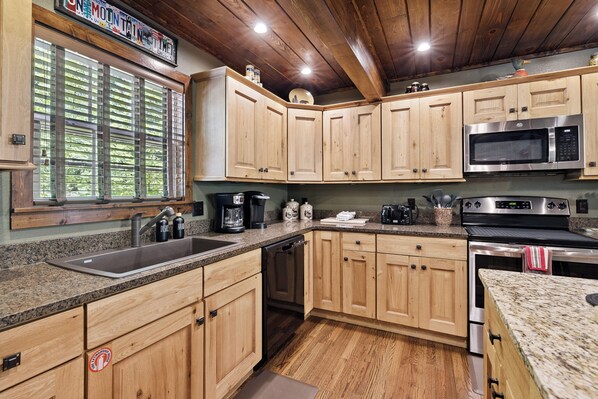 A modern kitchen with wooden cabinets, stainless steel appliances, and a granite countertop.