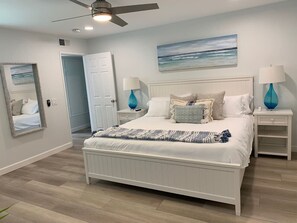 Relax in this serene bedroom with a large bed, two bedside tables, and a ceiling fan.