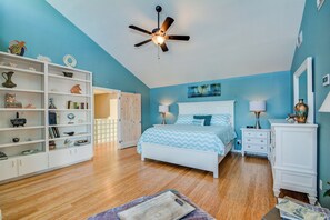 Une chambre à coucher avec un lit, un ventilateur de plafond, une bibliothèque et une commode.