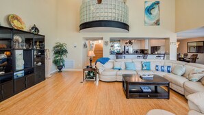 A spacious living room with a large sectional sofa, a coffee table, and a ceiling fan. - Lei by the Sea, Beautiful 2nd Row Beach House with Elevator (Galveston)