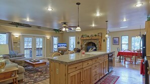 A spacious kitchen with a large island, wooden cabinets, and a stone fireplace. - Woodsy family getaway: private, hiking, wood stove, sleeps 12 (Parks)