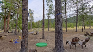 Relax in a serene forest setting with a swing, hammock, and Adirondack chairs.