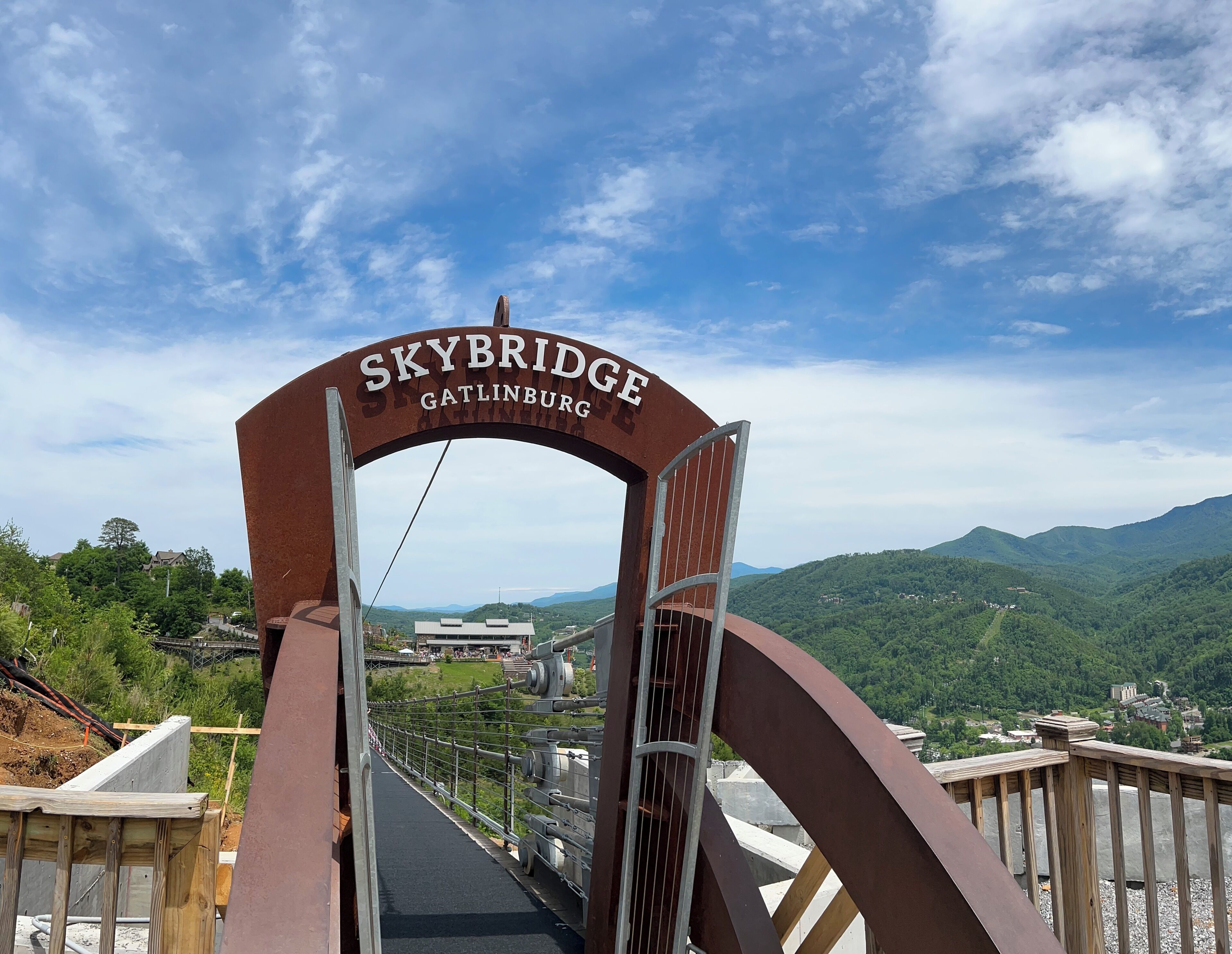A Skybridge entrance with a view of a green landscape and distant buildings.