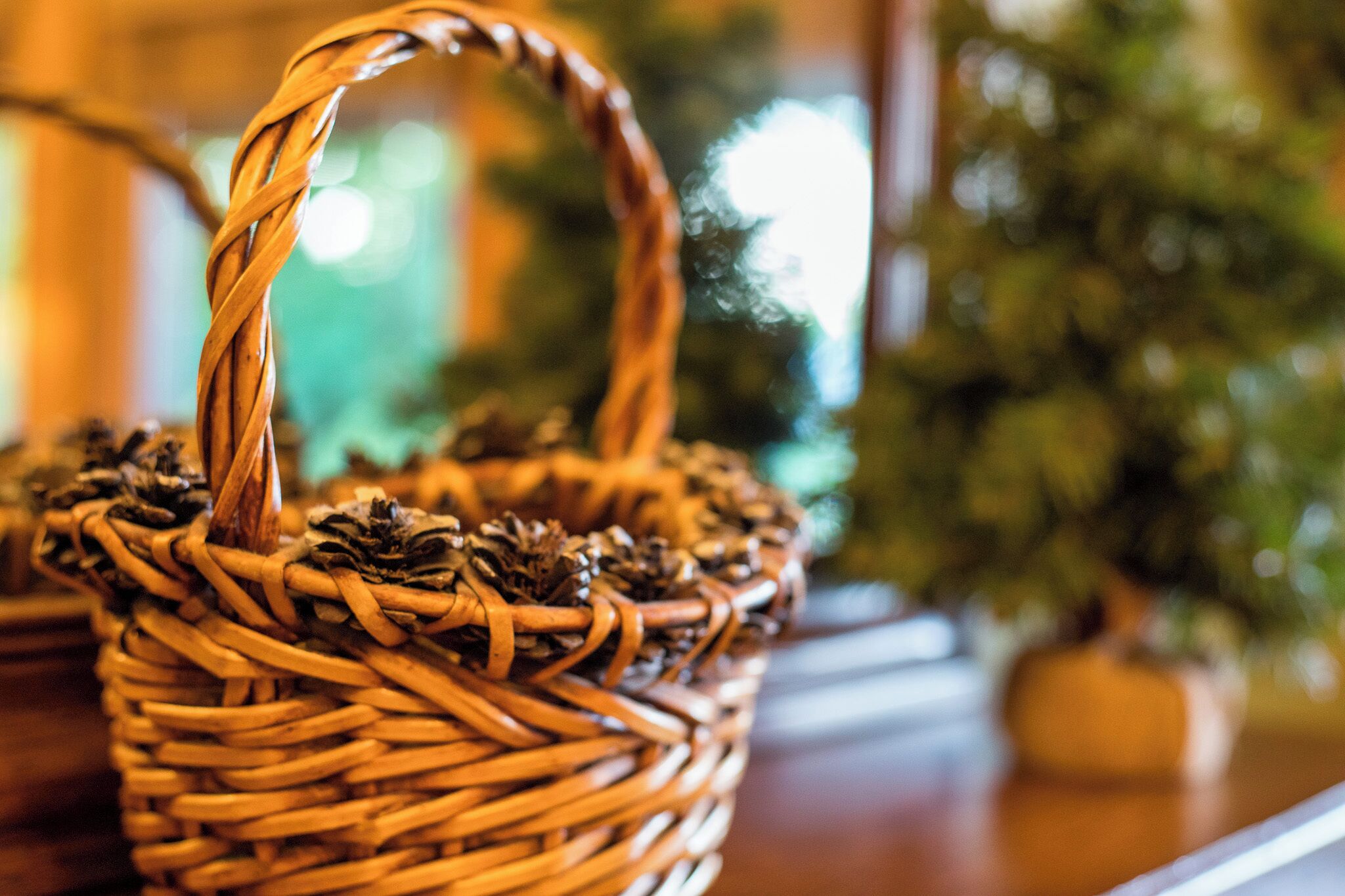 A wicker basket with pine cones on a wooden surface.