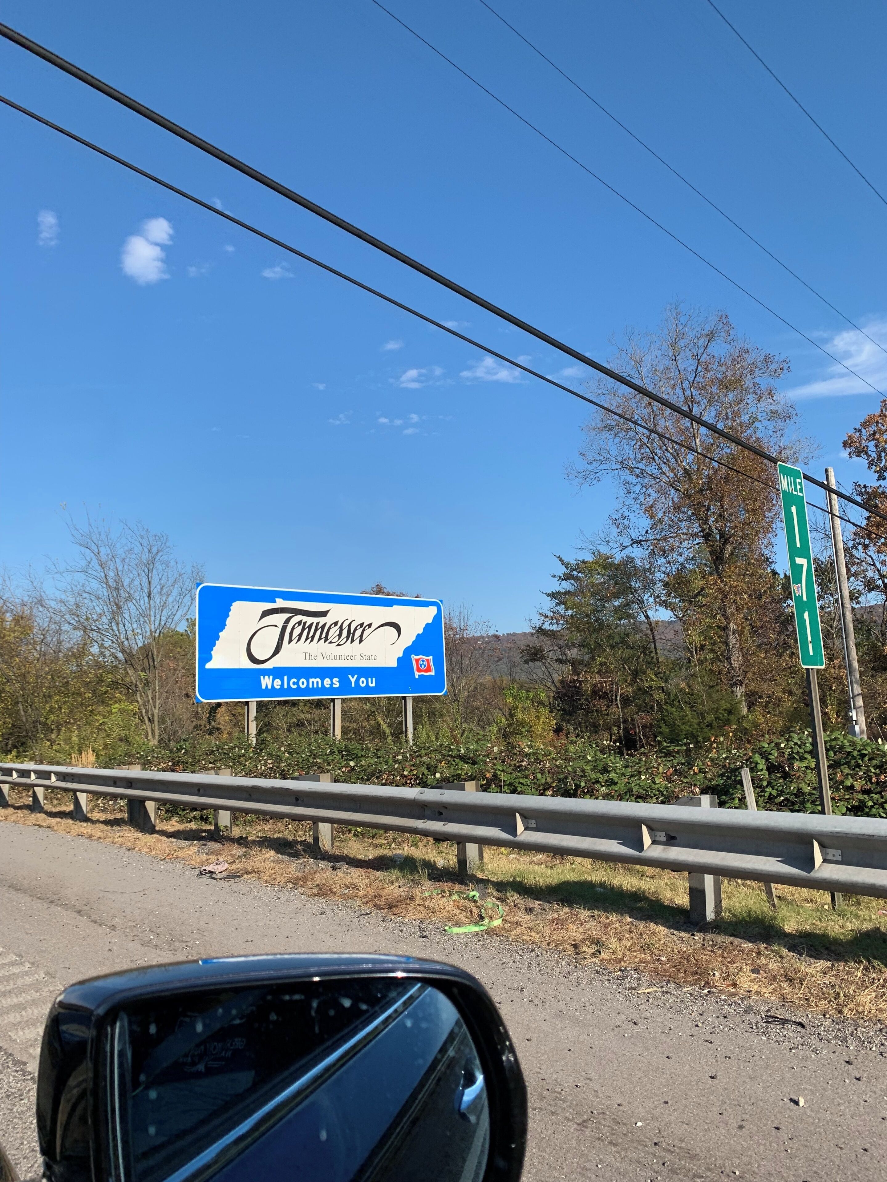 Een snelwegbord dat bezoekers verwelkomt in Tennessee, met een heldere lucht en begroeiing langs de weg.
