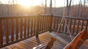 Une terrasse en bois avec une balançoire et un banc.