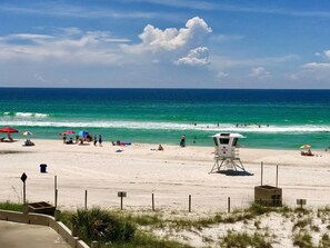 A beach with lifeguard towers, umbrellas, and people enjoying the water.
