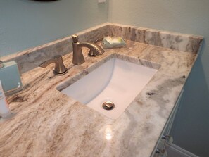 A bathroom with a marble sink, two faucets, and a soap dish.