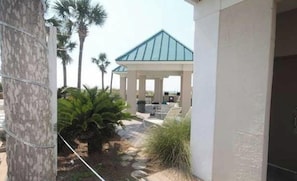 A covered outdoor area with seating, palm trees, and a stone pathway.