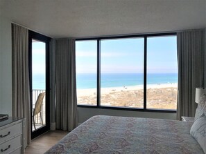 Ein Schlafzimmer mit einem großen Fenster und Blick auf Strand und Meer.