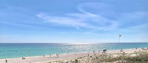 Ein Strand mit einem Rettungsturm, blauem Himmel und ruhigem Wasser.