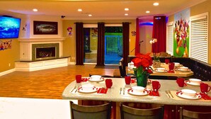 A dining area with a table set for four, a fireplace, and a television mounted on the wall.