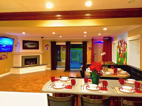 A dining area with a table set for four, a fireplace, and a television mounted on the wall.