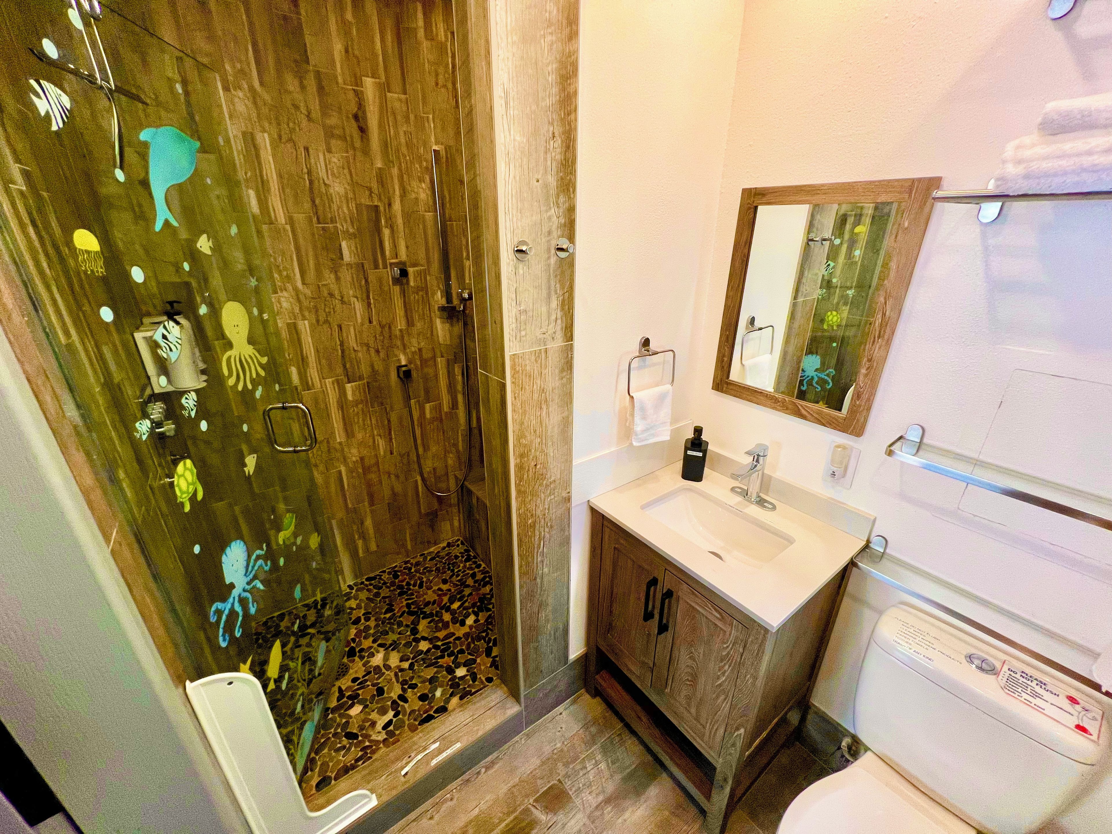 Une salle de bain avec une cabine de douche en bois, un lavabo avec un miroir et des toilettes.
