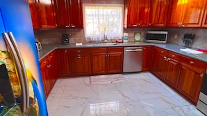 A kitchen with wooden cabinets, a stainless steel refrigerator, a microwave, and a dishwasher.