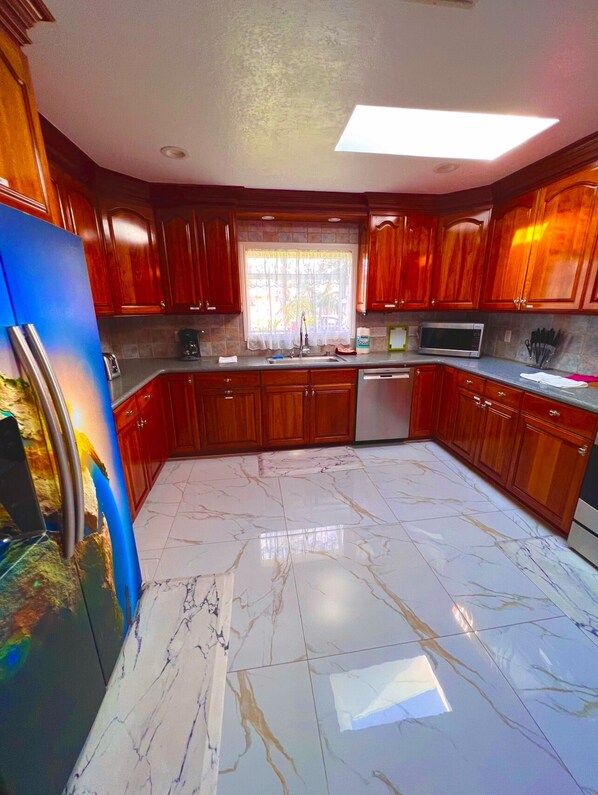Una cocina con armarios de madera, un refrigerador de acero inoxidable, un microondas y un lavavajillas.