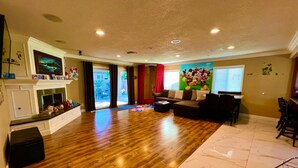 Un salon spacieux doté d’un plancher en bois franc, d’une cheminée, d’un canapé et d’un coin repas.