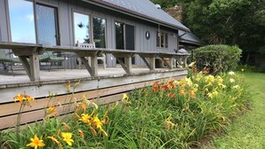 A house with a wooden deck and a garden with yellow flowers. - Stunning Views, close to Wineries, Primland & Parkway - beautifully appointed (Meadows of Dan)