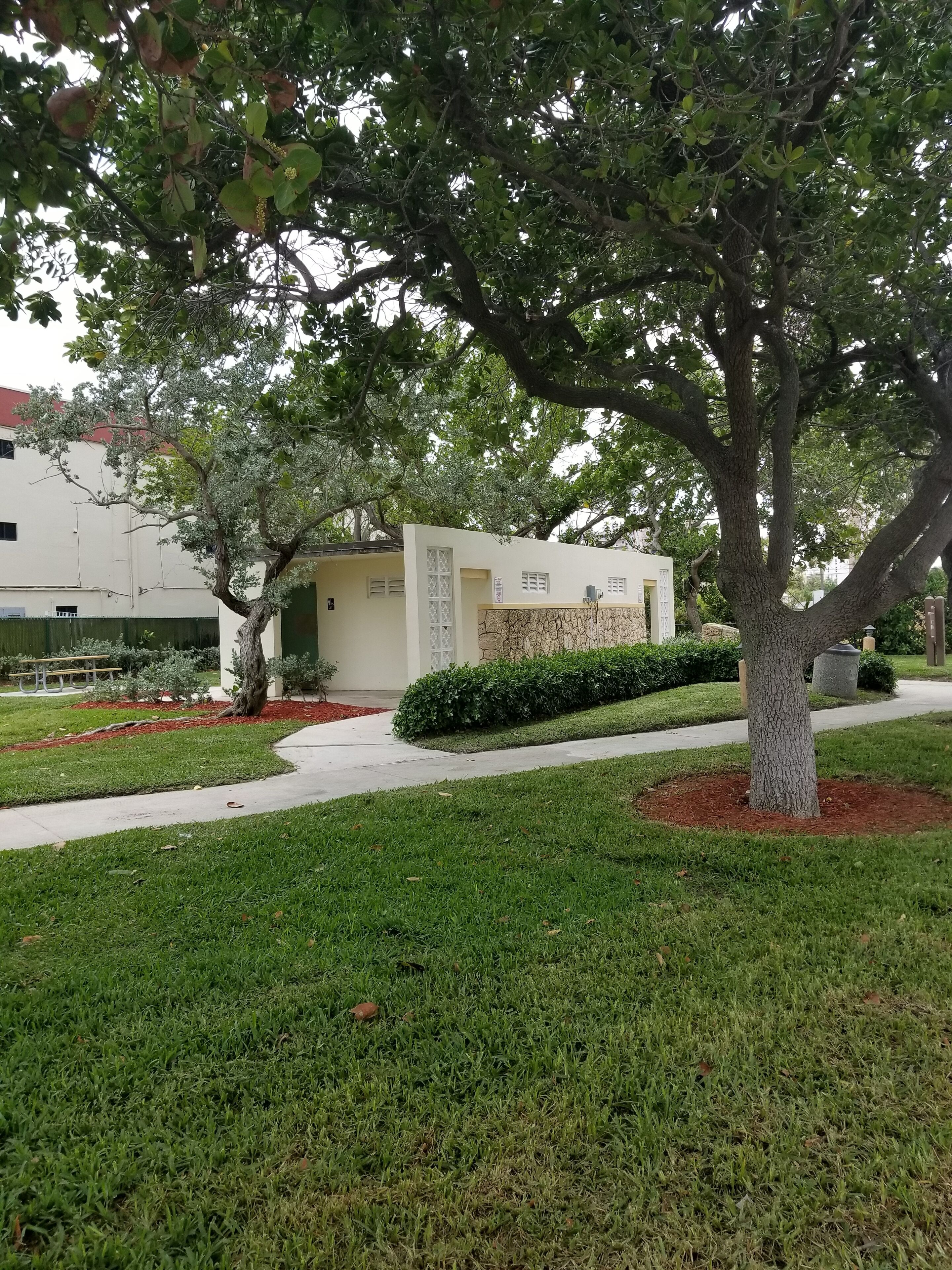 A building with a white exterior, surrounded by well-maintained grass and a tree.