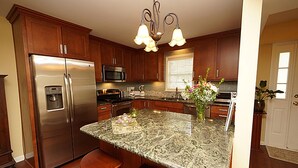A kitchen with wooden cabinets, stainless steel appliances, a granite countertop, and a bar stool. - Beautiful Townhome 10 min from Charleston & Beaches, Pool, Tennis Court! (Charleston)