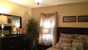 A bedroom with a bed, dresser, lamp, curtains, and a plant. - Beautiful Townhome 10 min from Charleston & Beaches, Pool, Tennis Court! (Charleston)