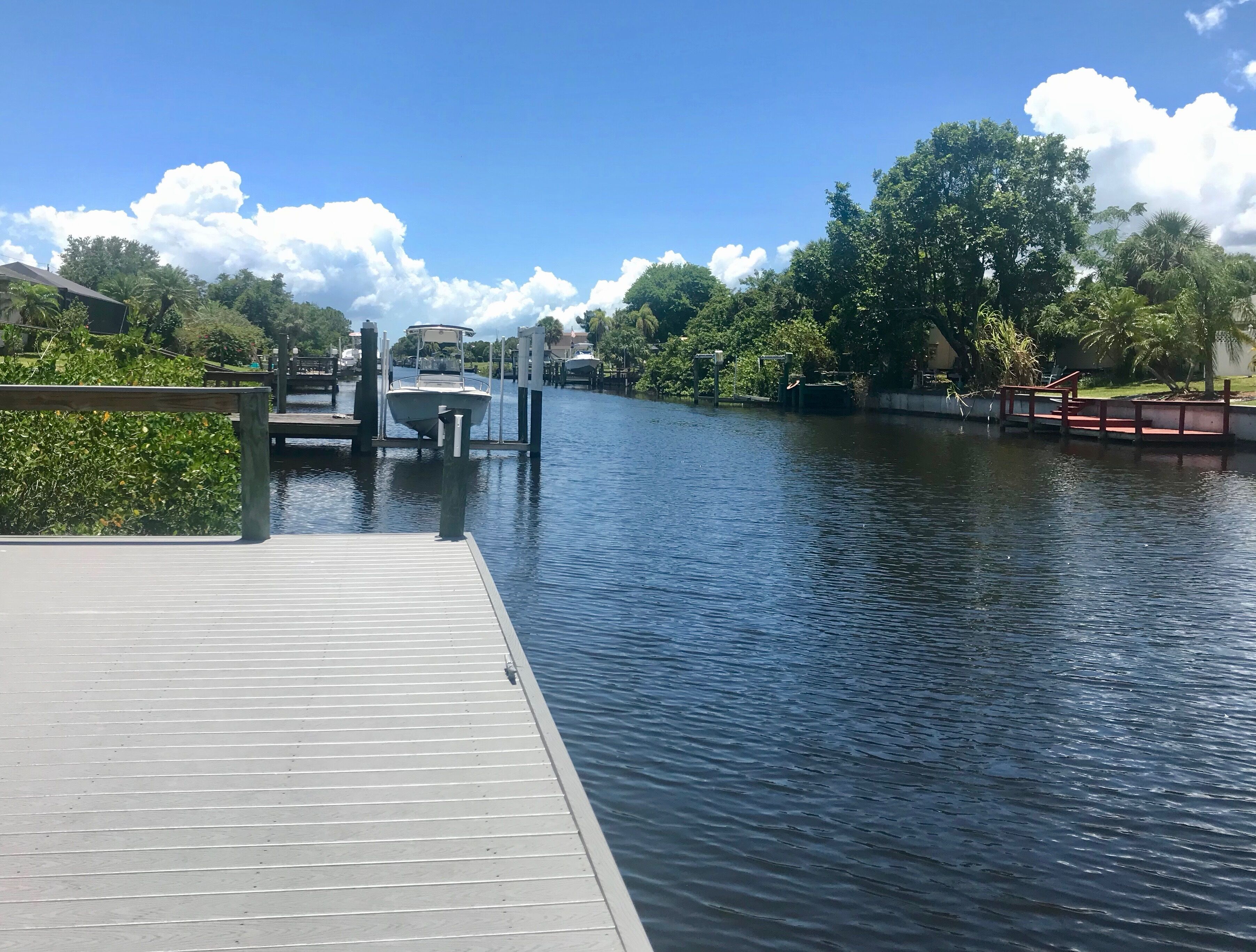 A calm river with a wooden dock and a boat docked at the pier.