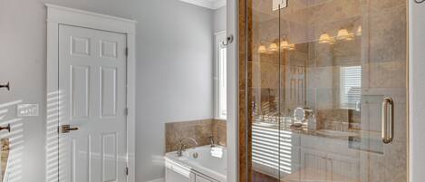 A modern bathroom with a glass shower enclosure, a white door, and a built-in sink.