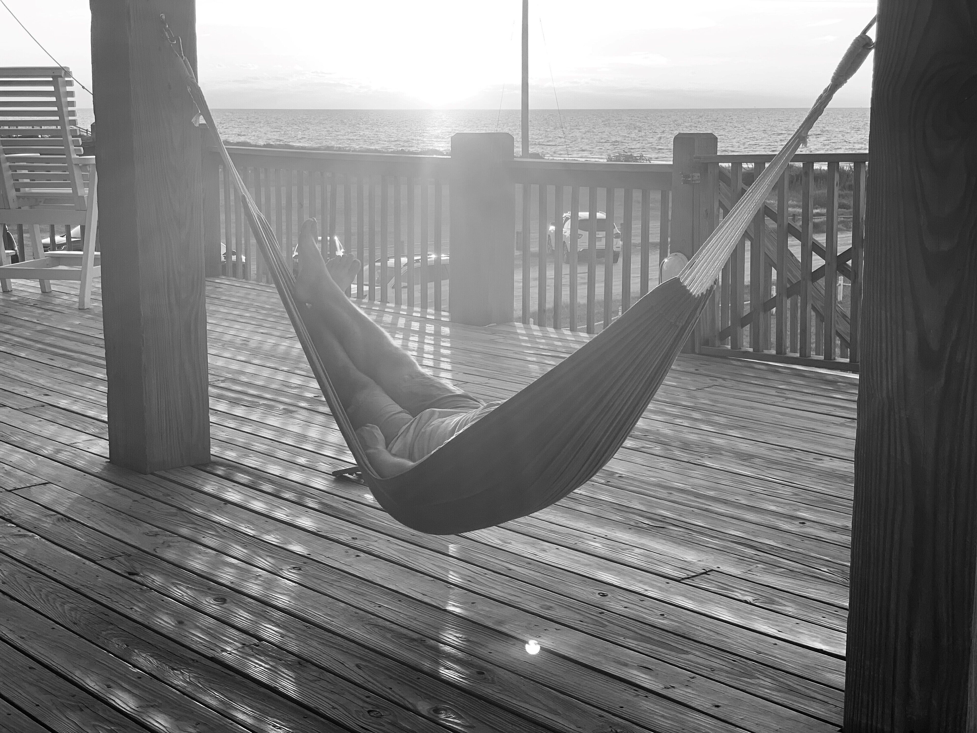 Una hamaca sobre una terraza de madera con vista al océano.