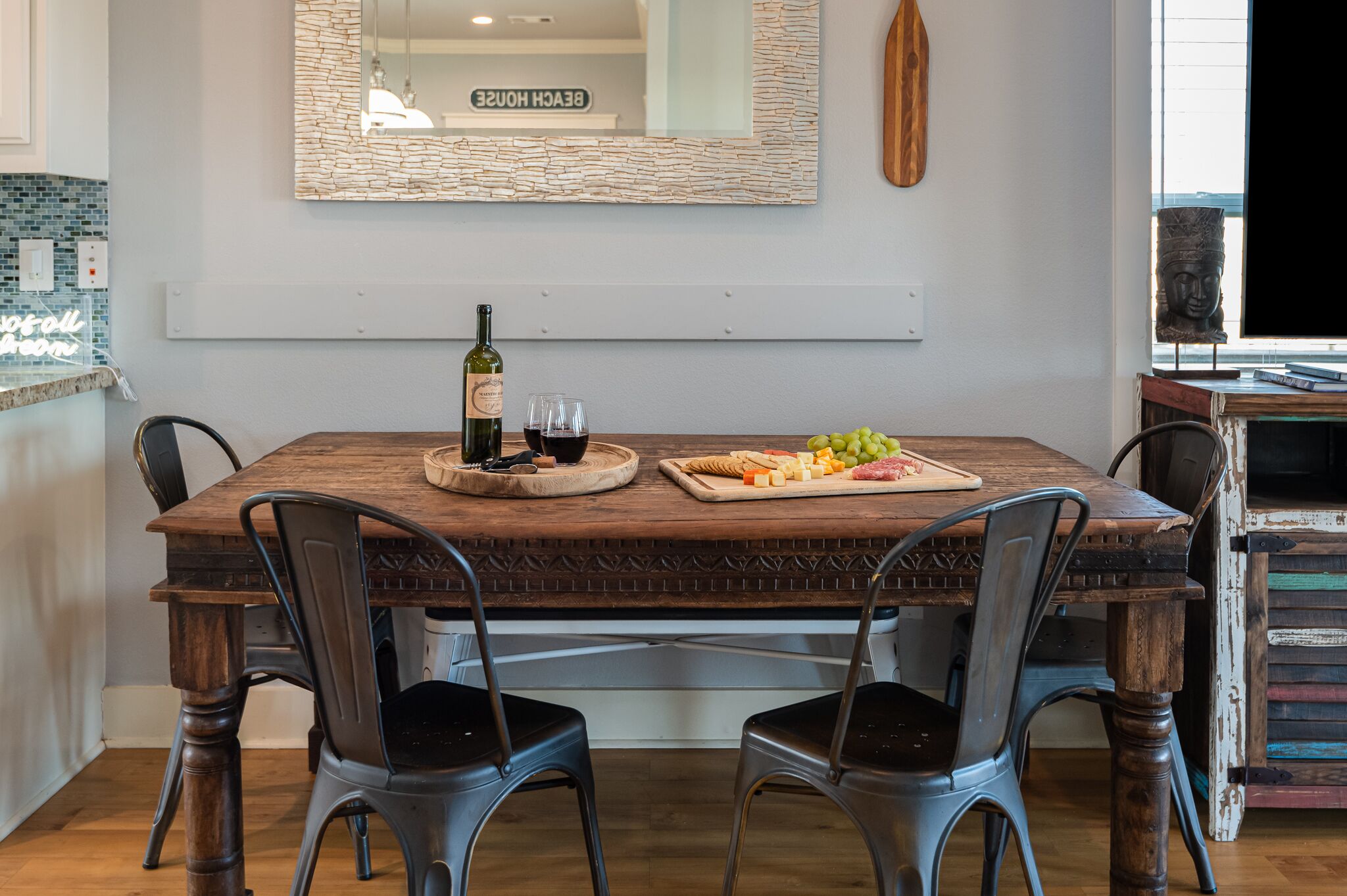 Une table à manger avec une bouteille de vin, des verres et une planche à fromage.