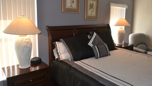 A neatly made bed with a dark headboard, two bedside lamps, a nightstand with a lamp, and two framed pictures on the wall. - Orlando Villa near Disney, free Private Heated Pool, free Grill and free WiFi (Davenport)