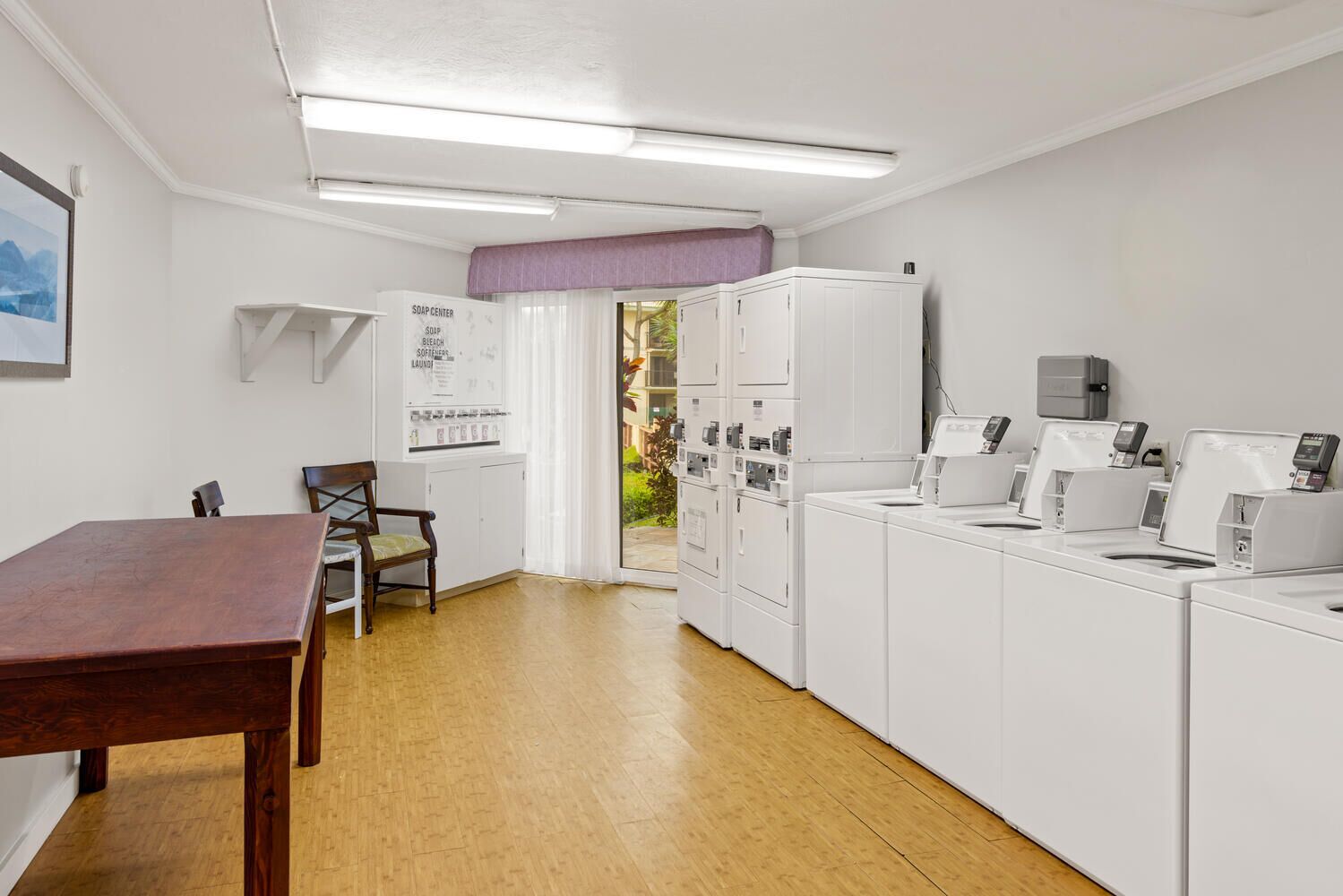 Un cuarto de lavandería con una mesa de madera, sillas y un gabinete blanco con la etiqueta "SOAP CENTER".