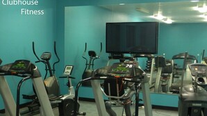 A fitness room with treadmills, stationary bikes, and a television screen.