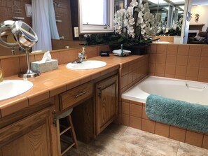 A bathroom with two sinks, a mirror, a towel rack, and a bathtub.