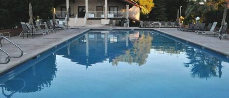 A swimming pool with lounge chairs and a building in the background.