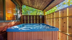 Un jacuzzi en una cabaña de madera con vistas a árboles.