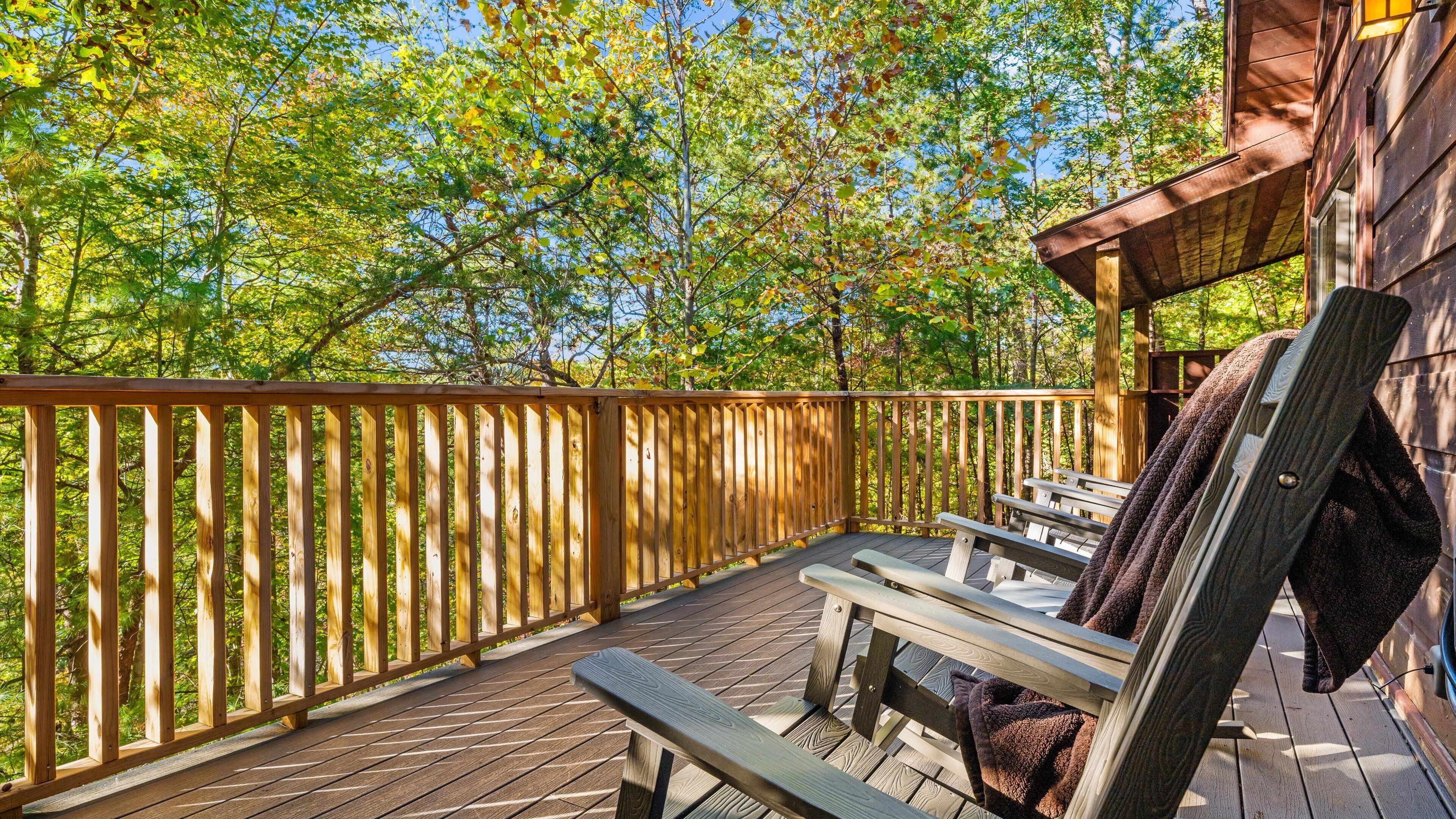 A wooden deck with a railing, benches, and a covered area with a table and chairs.