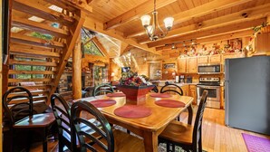 Ein Holzblockhaus-Innenraum mit Essbereich, Küche und Kamin.