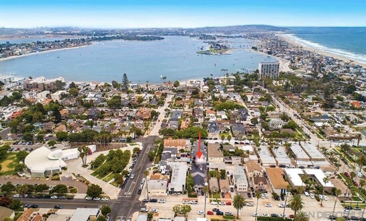 Une vue aérienne d’une ville côtière, avec des zones résidentielles, une étendue d’eau importante et un bâtiment imposant doté d’un toit en forme de flèche.