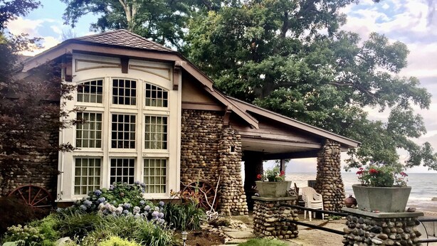 A stone building with large windows and a covered patio overlooking a body of water. - Beachfront Historic home 2br/1Ba apt. w/  Steam Shower, WiFi, Netflix, Disney+  (Dunkirk)