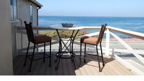A deck with two chairs and a table, overlooking the ocean.